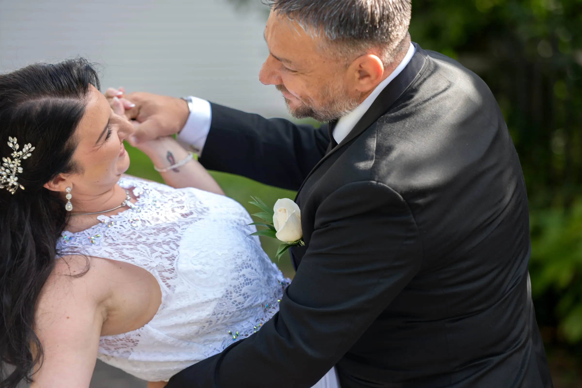 The groom carefully adjusting the bride’s hairpiece while she looks up at him