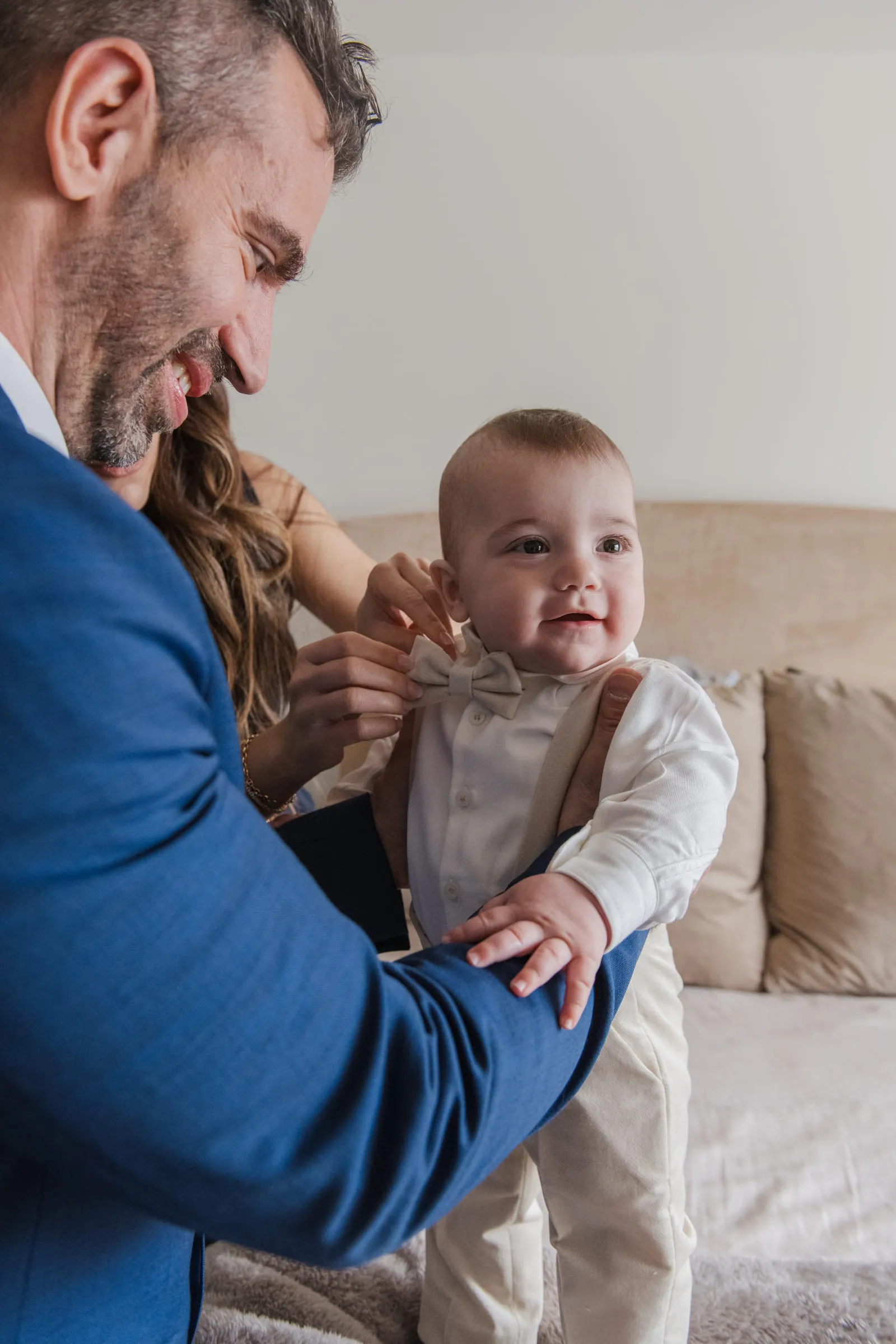 The baby’s father fastening his outfit while the baby smiles up at him