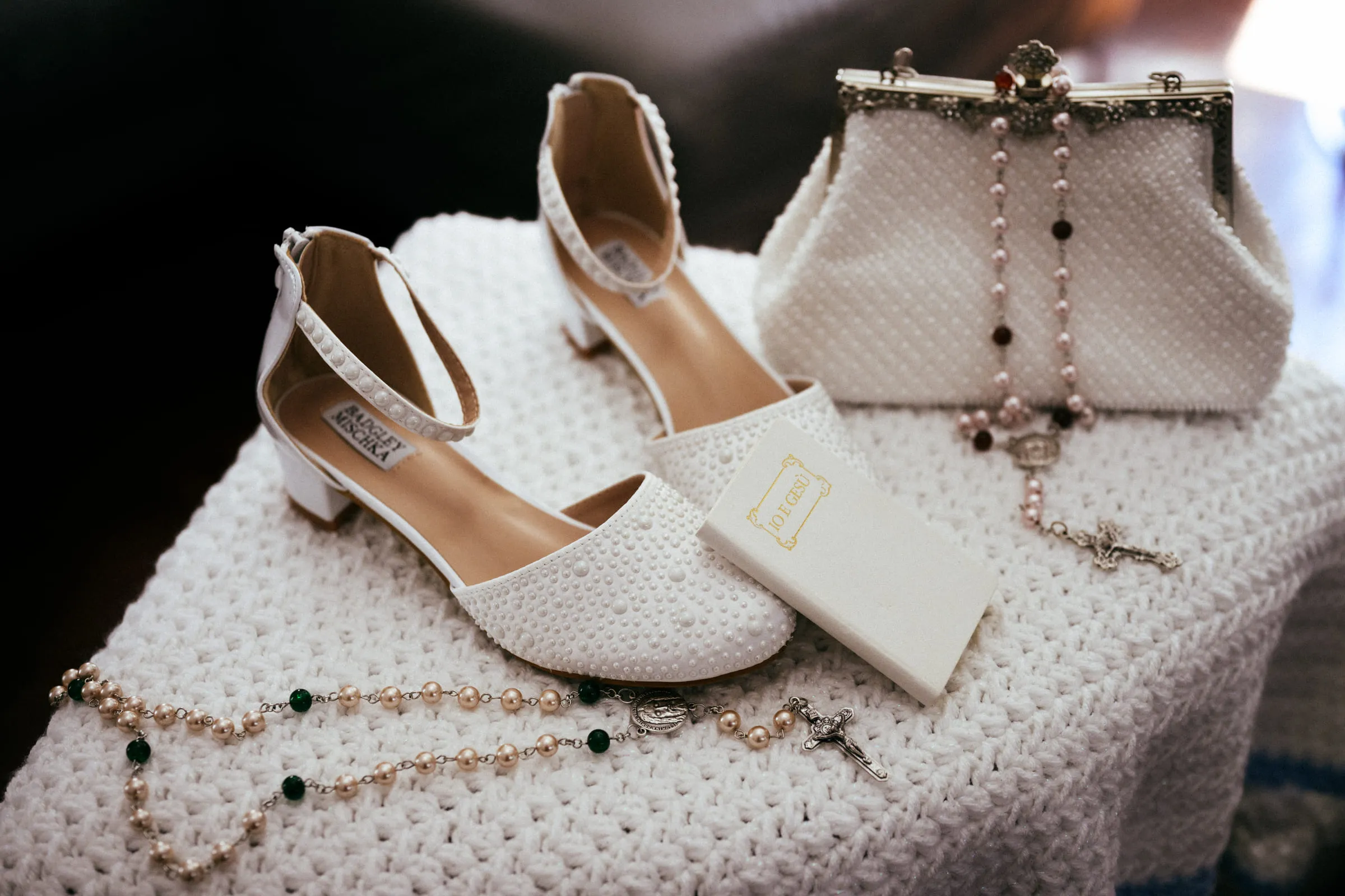Communion shoes, a beaded purse, a rosary and a white missal laid out together