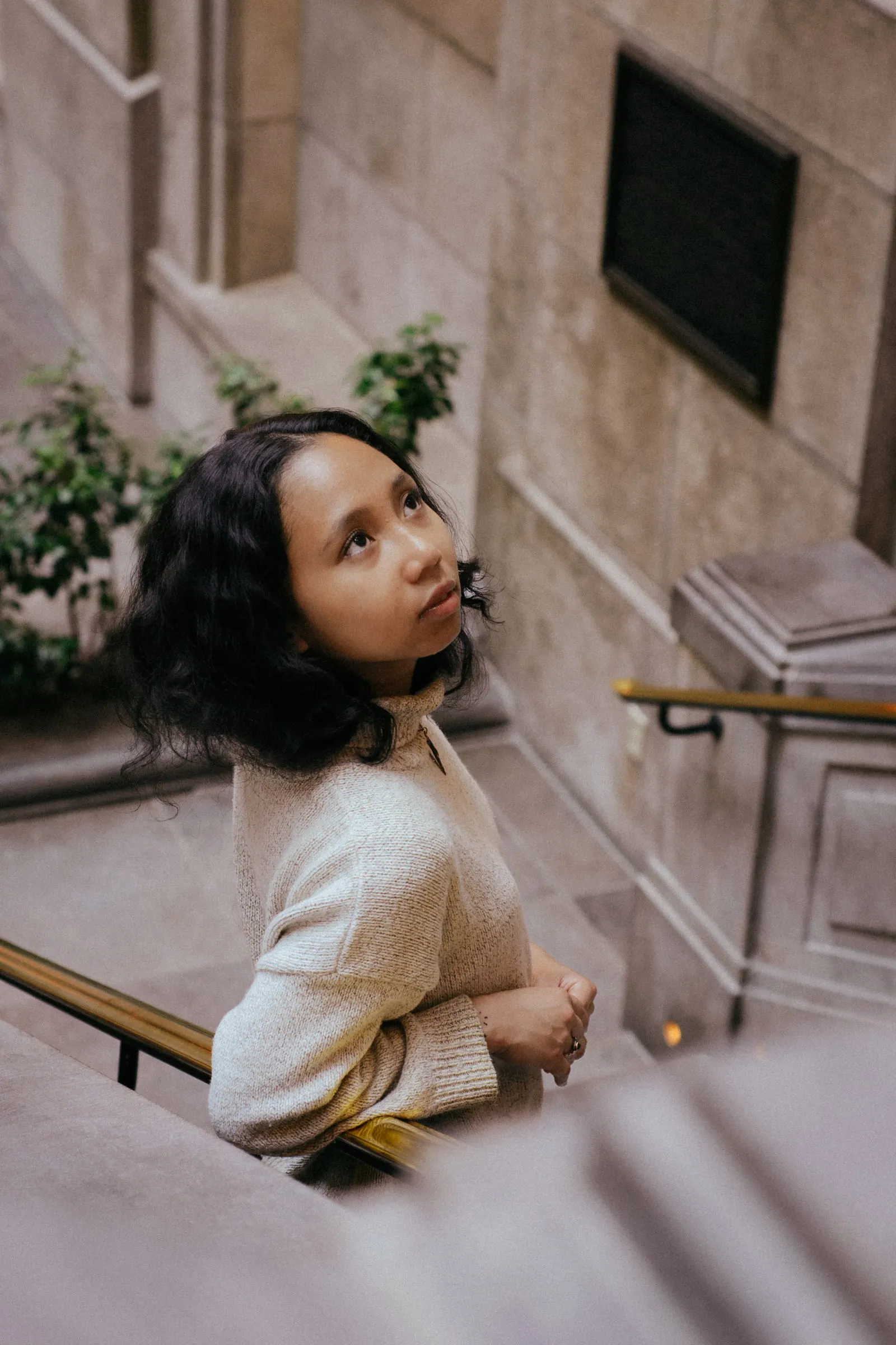 A young woman leaning on a stone balustrade, looking upward