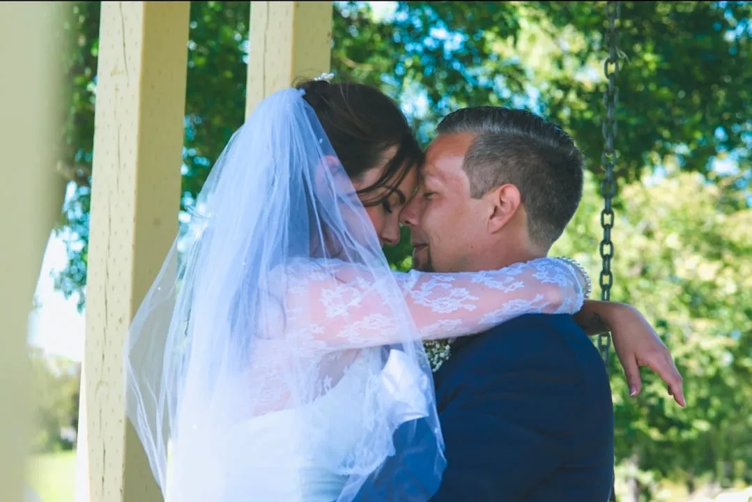 A bride and groom leaning in to kiss beneath her veil in a garden gazebo