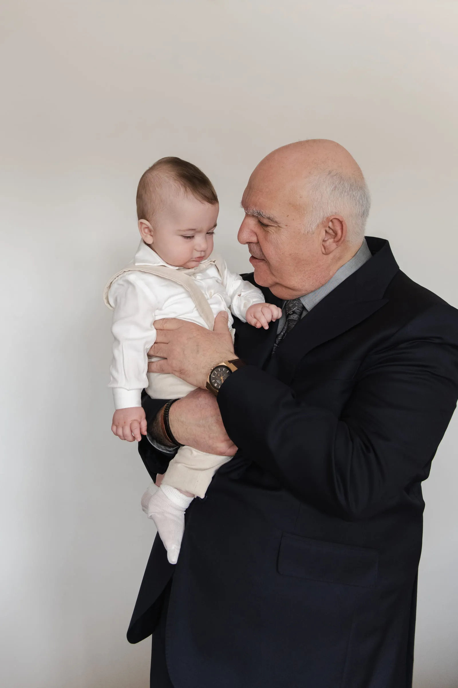 An older relative holding the baby, the two of them looking at each other