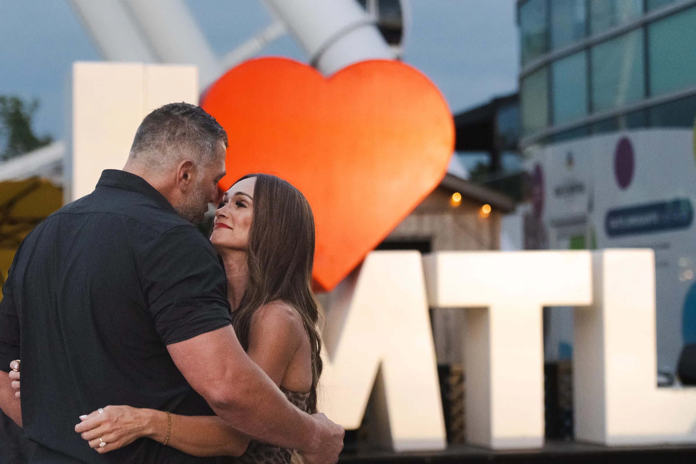 The couple embracing in front of the MTL letters and the big orange heart
