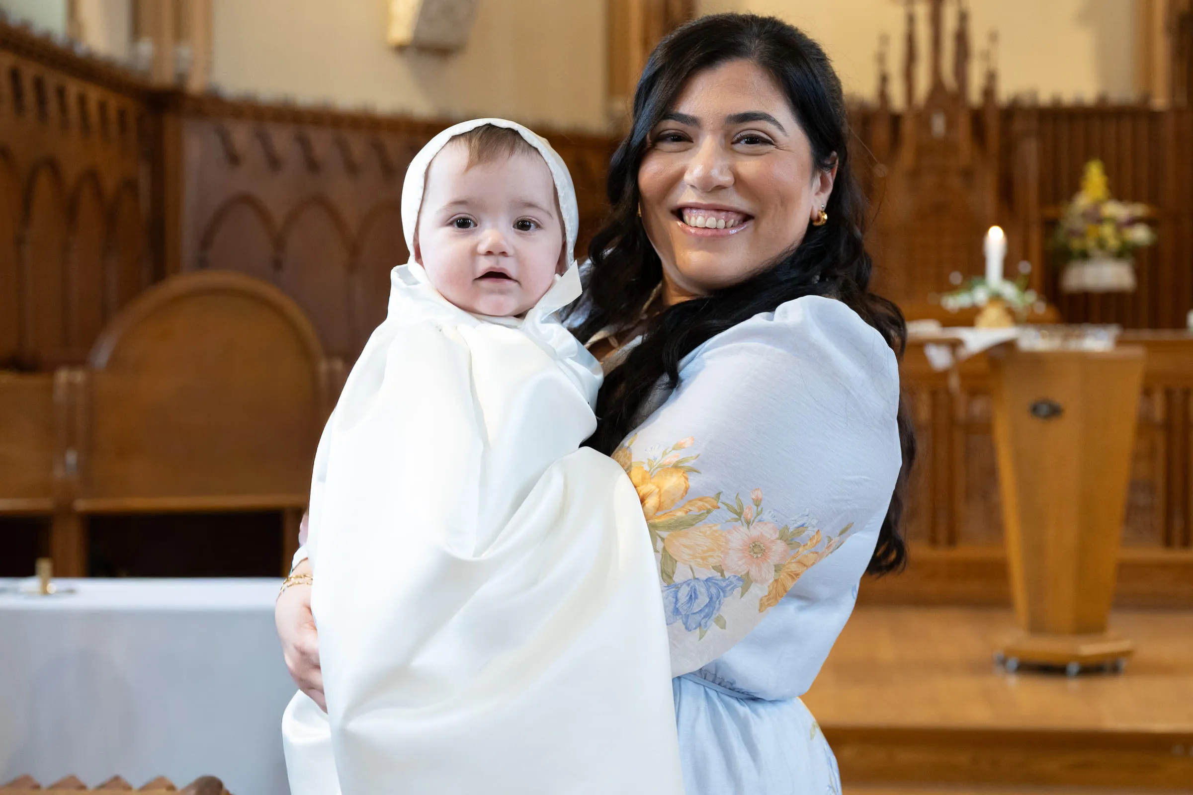 The baby’s mother holding him over her shoulder at the front of the church