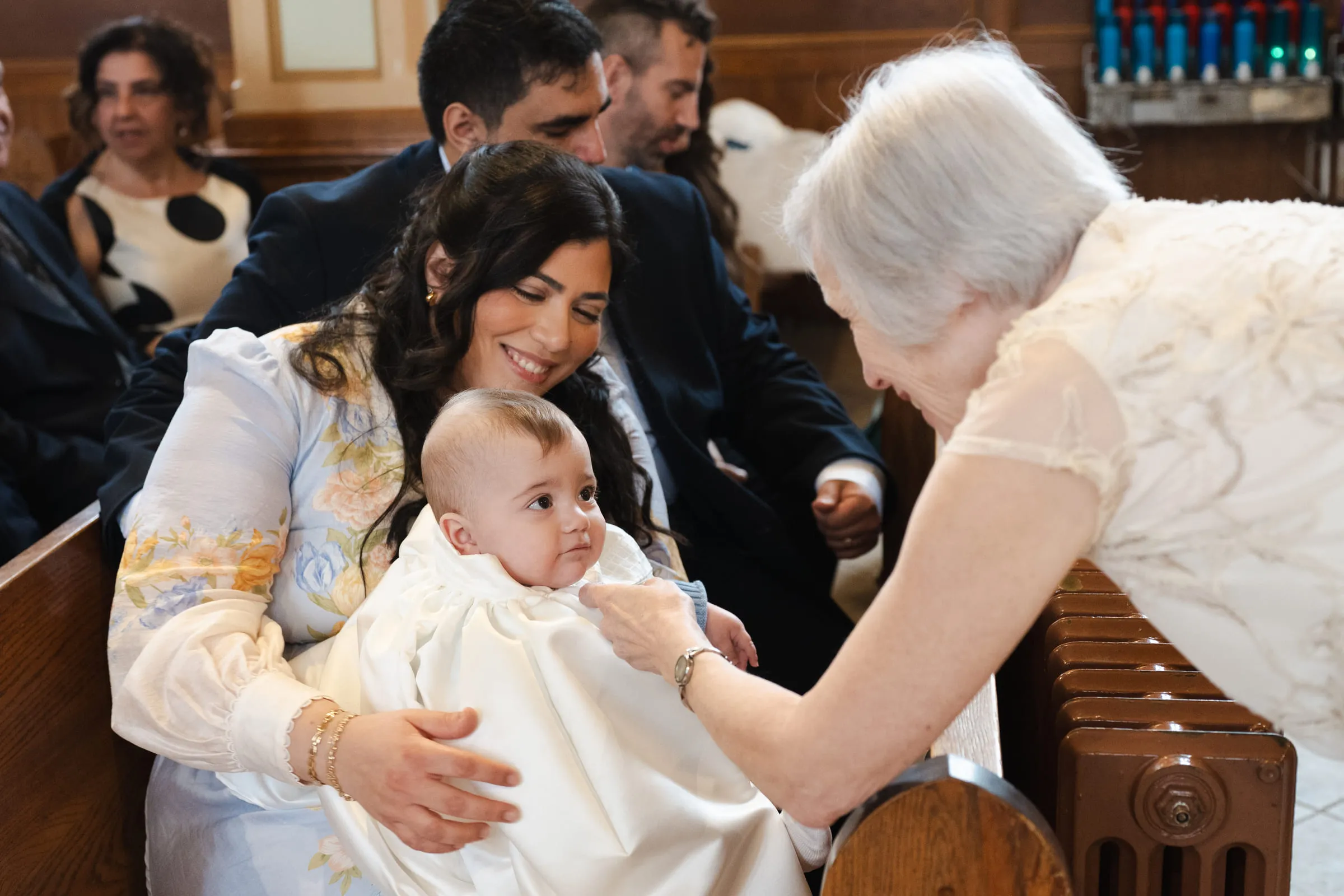 An older relative leaning in to greet the baby in his mother’s arms