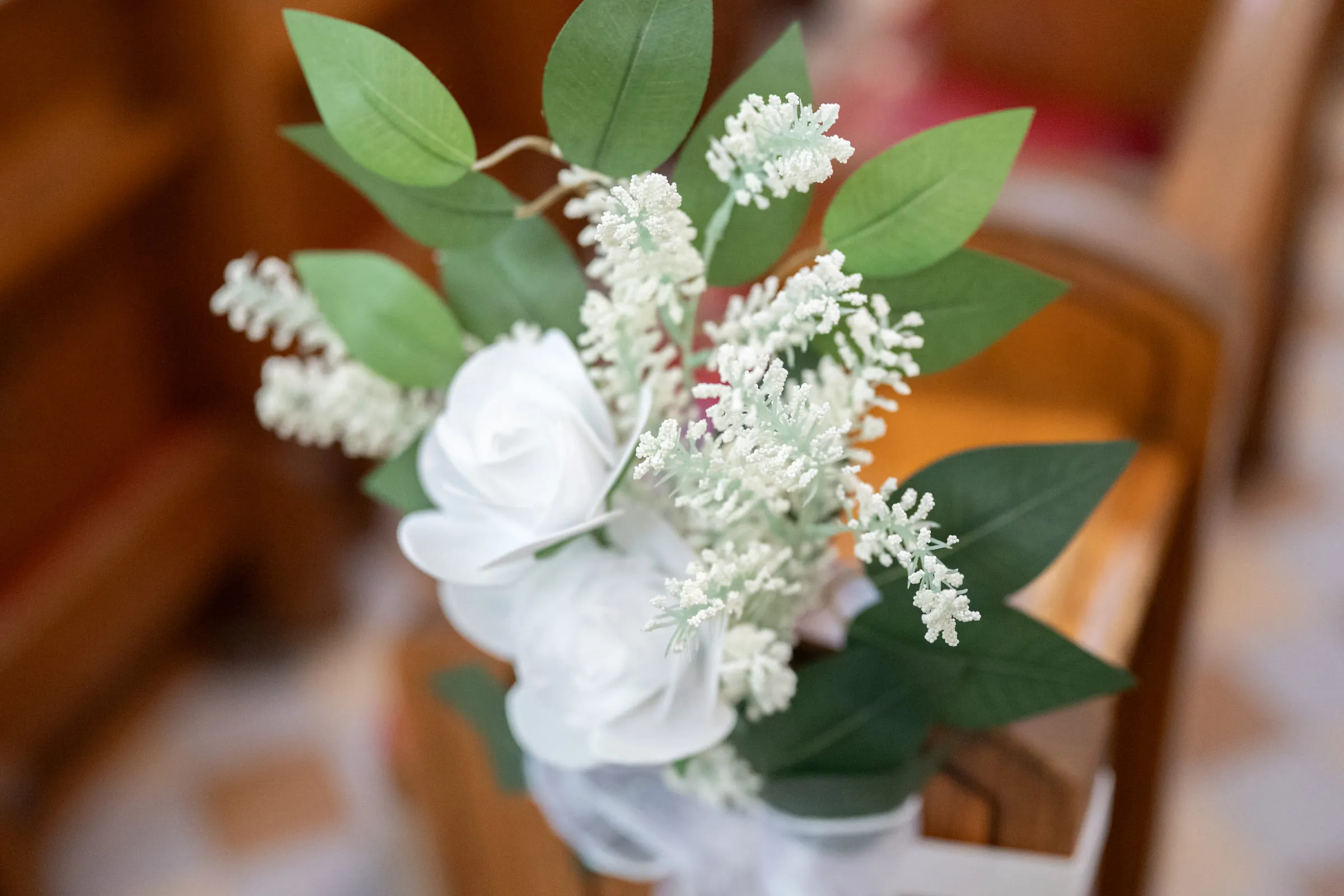 A small spray of white flowers and eucalyptus fixed to the end of a pew