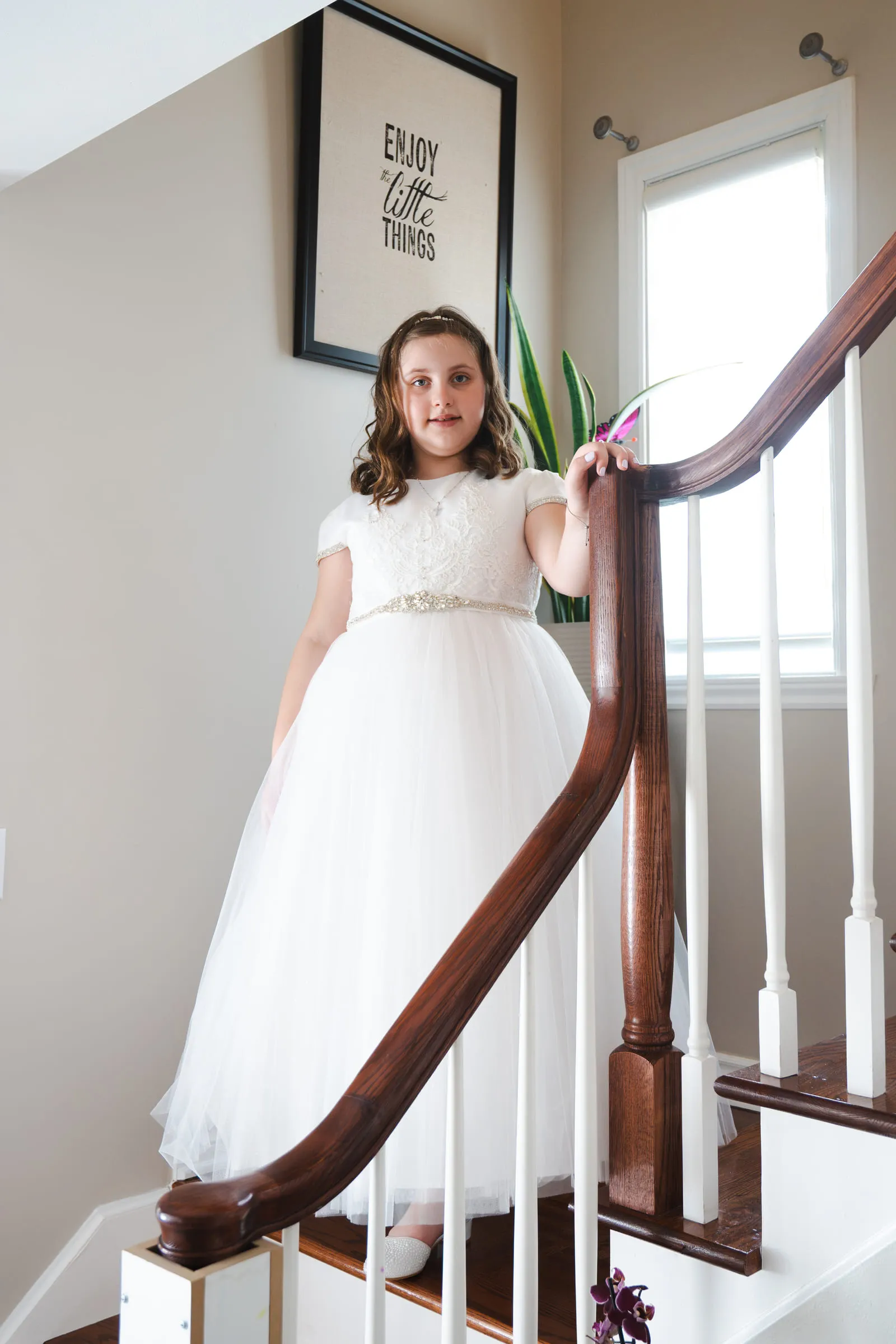 The girl standing at the top of the staircase in her communion dress