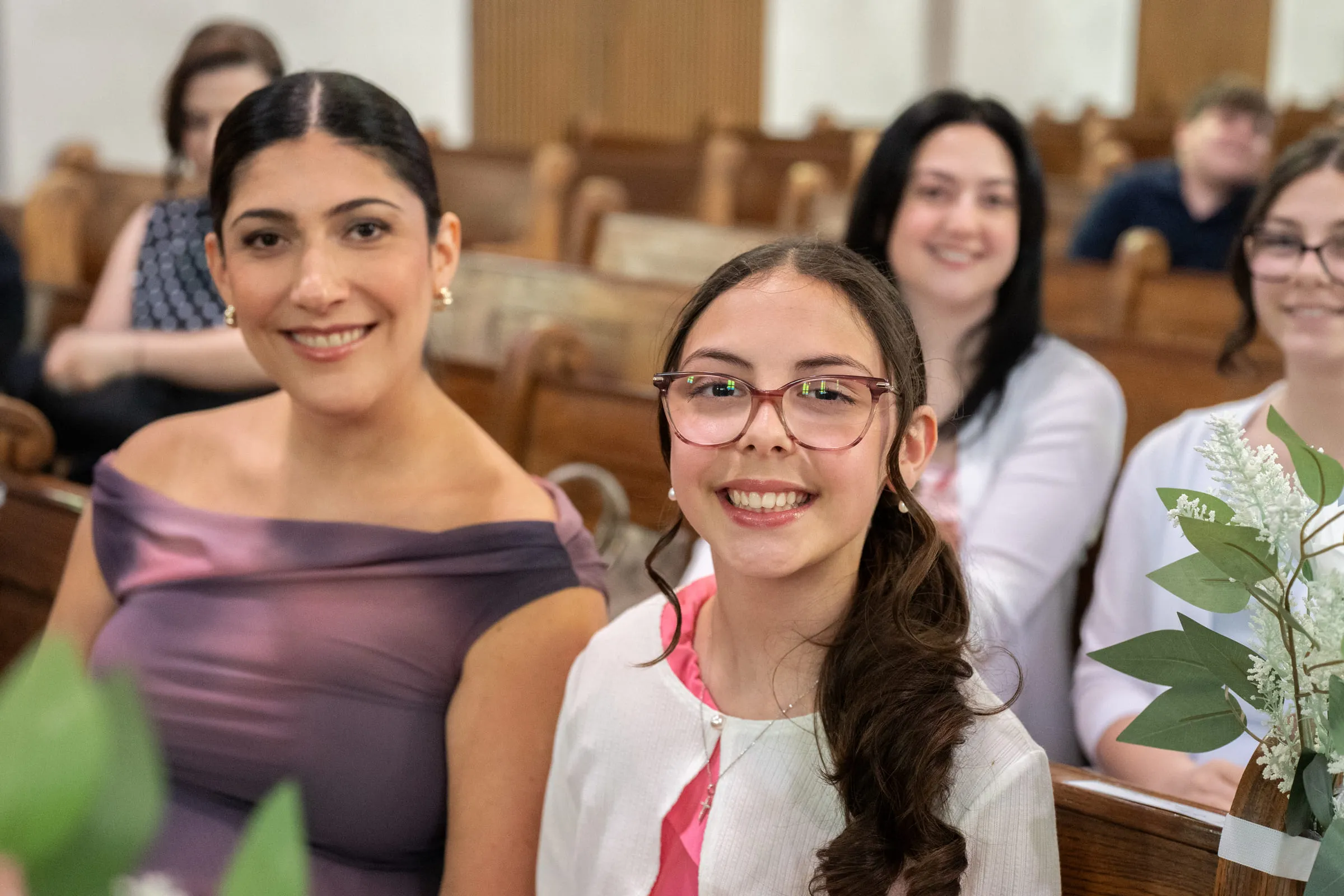 A mother and daughter smiling in the pew before the ceremony begins