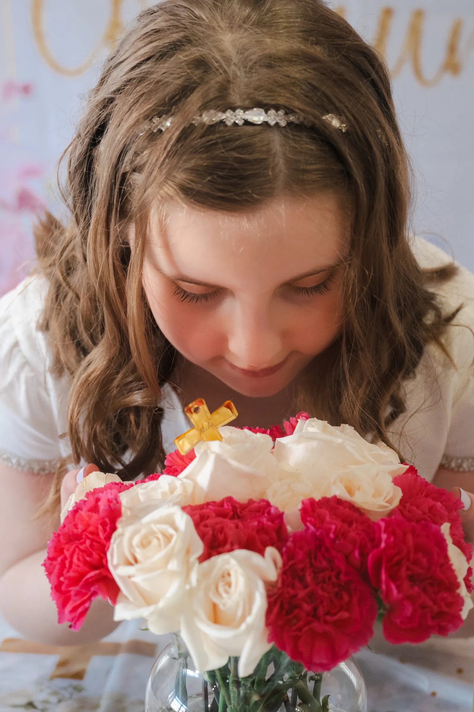 The girl leaning in to smell a bouquet of red and white carnations