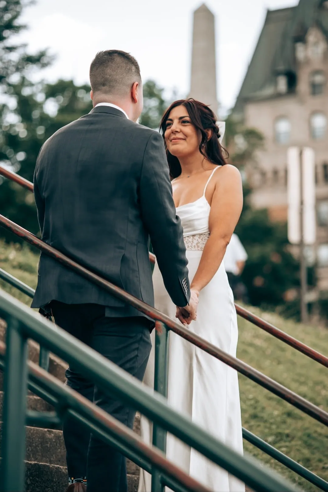 A bride smiling at her groom on a flight of stone steps, a château rising behind them