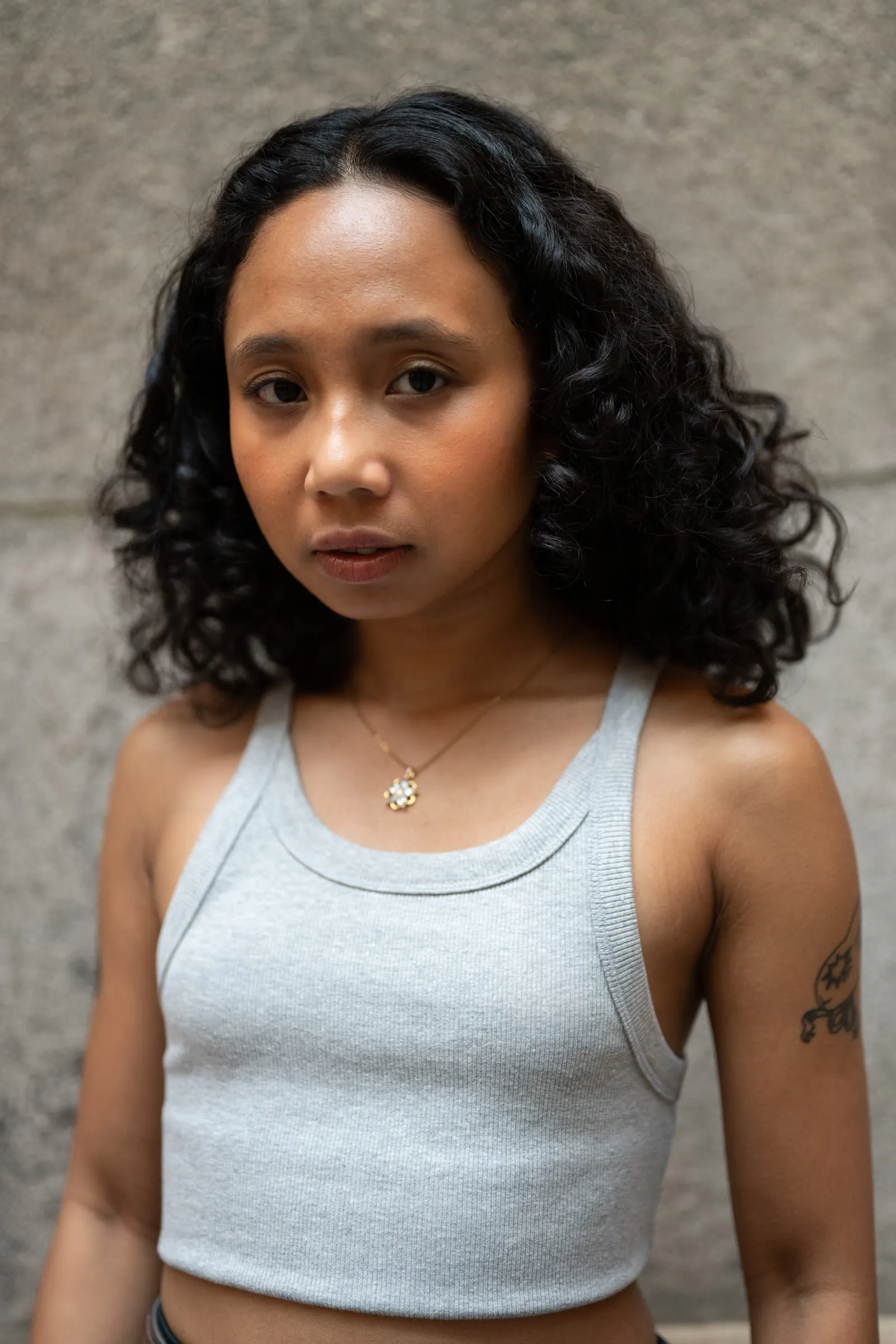 A close portrait of a young woman with curly hair looking straight at the camera