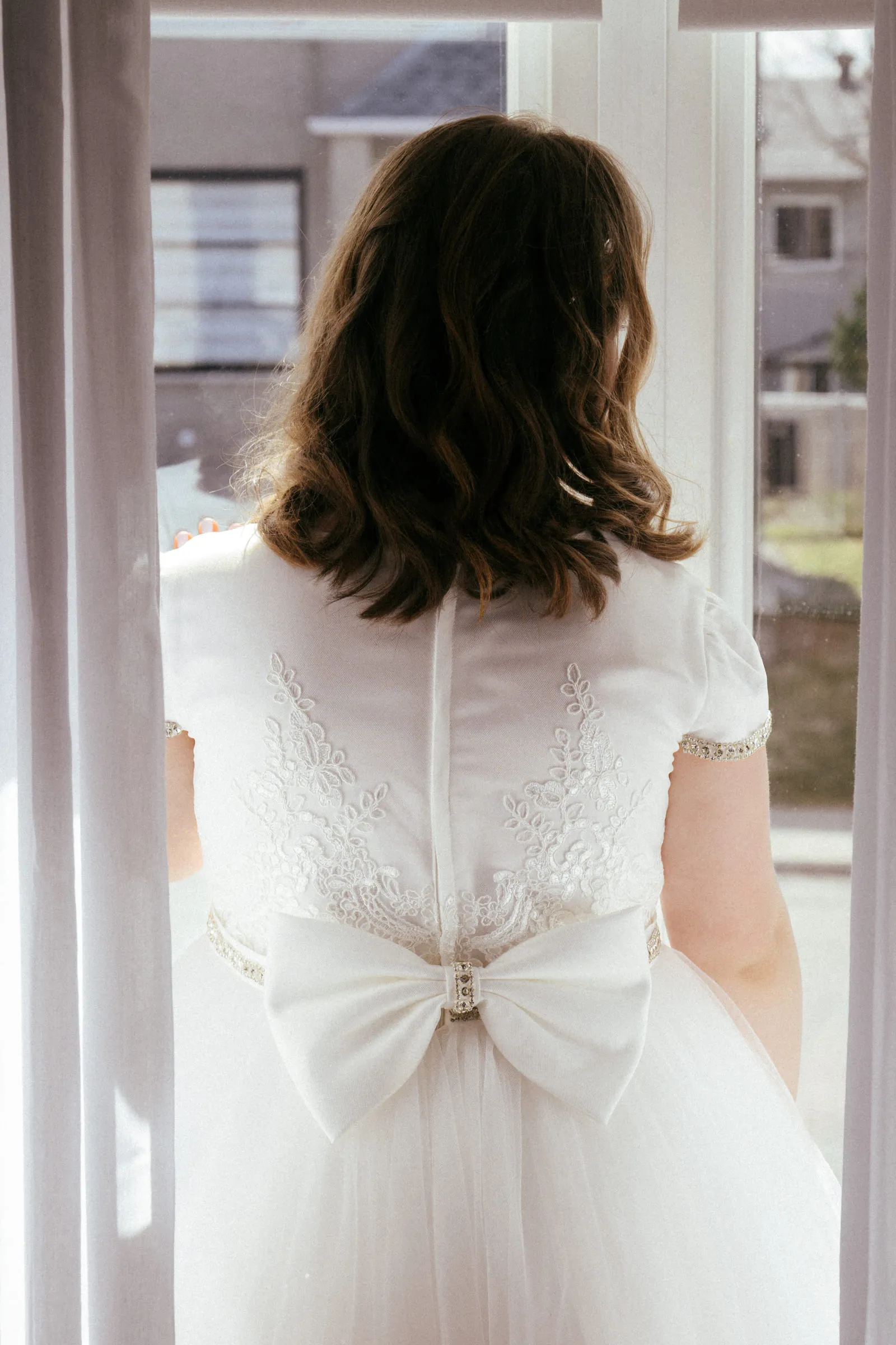The back of the communion dress and its large bow, in soft window light
