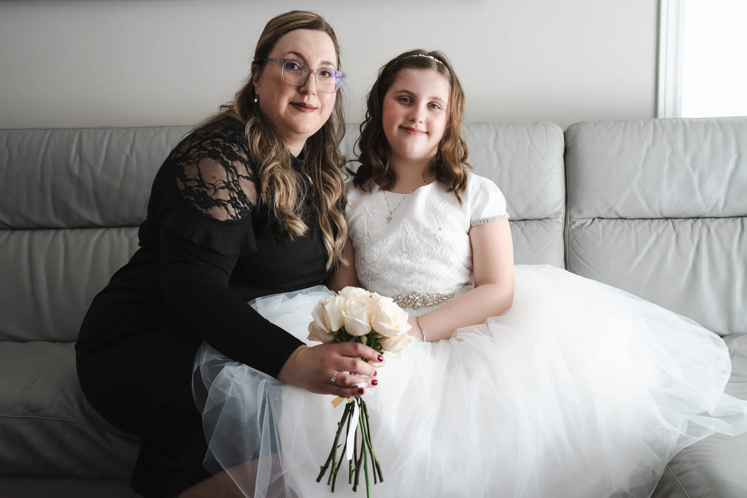 The girl and her mother seated together, the bouquet across her lap