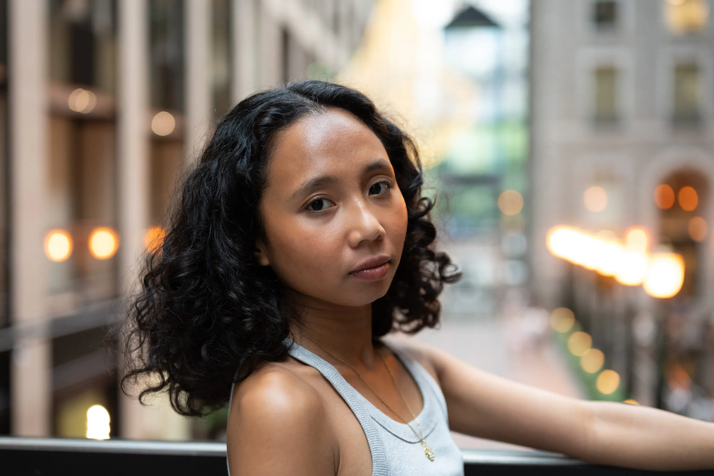 A young woman leaning on a railing, the street behind her falling out of focus