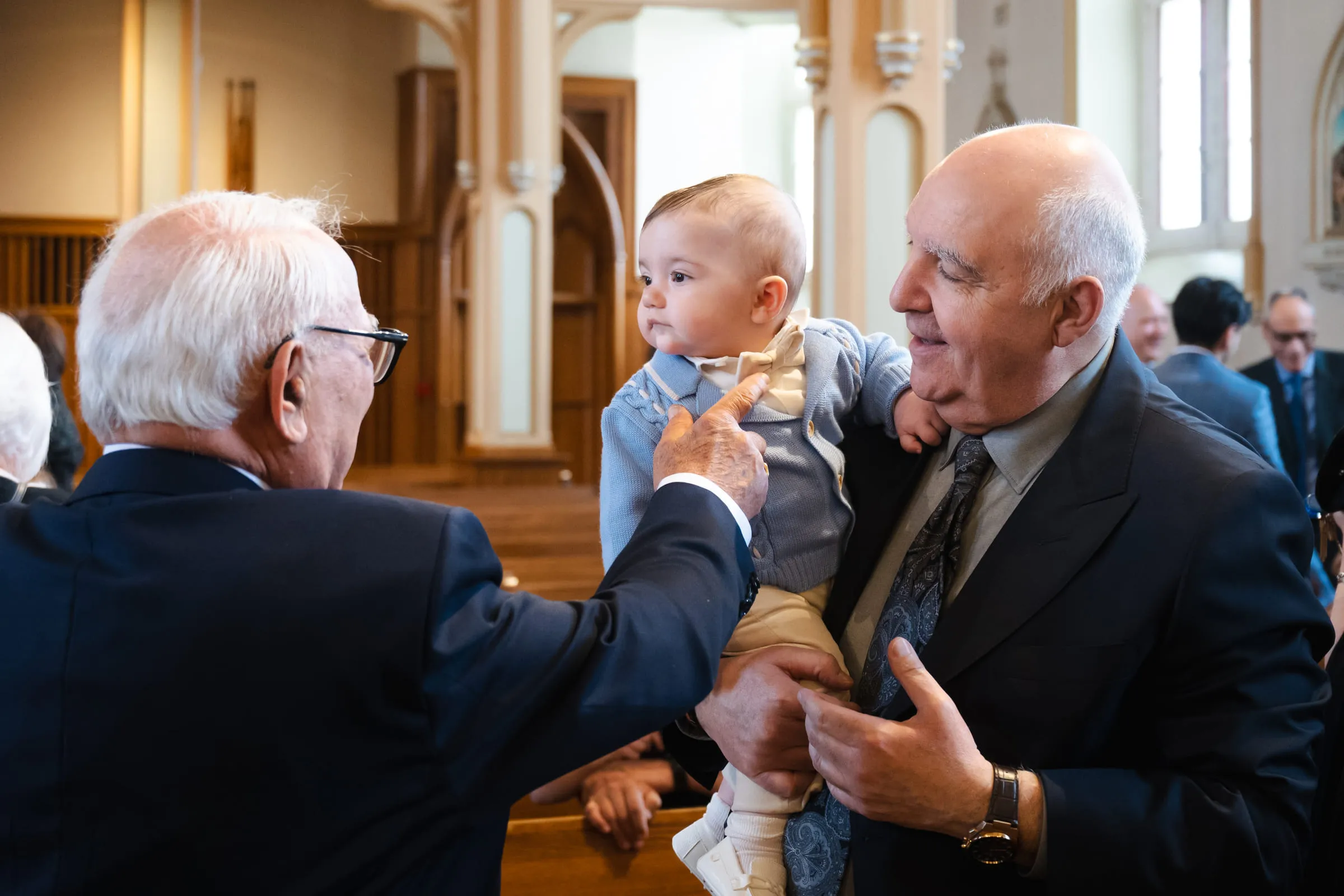 The baby lifted between two older relatives after the ceremony, everyone laughing