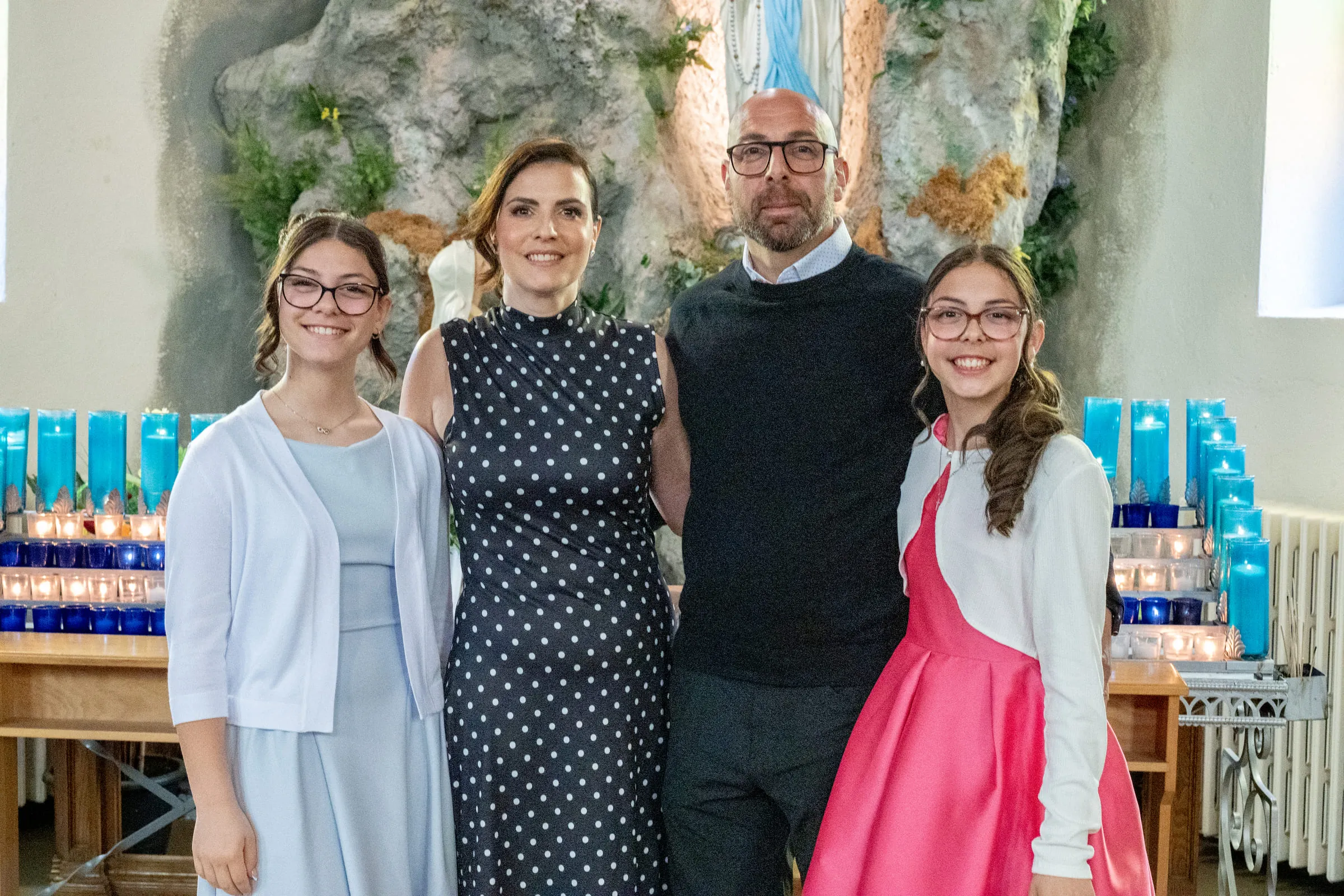 Parents and daughters in front of the shrine and its bank of votive candles