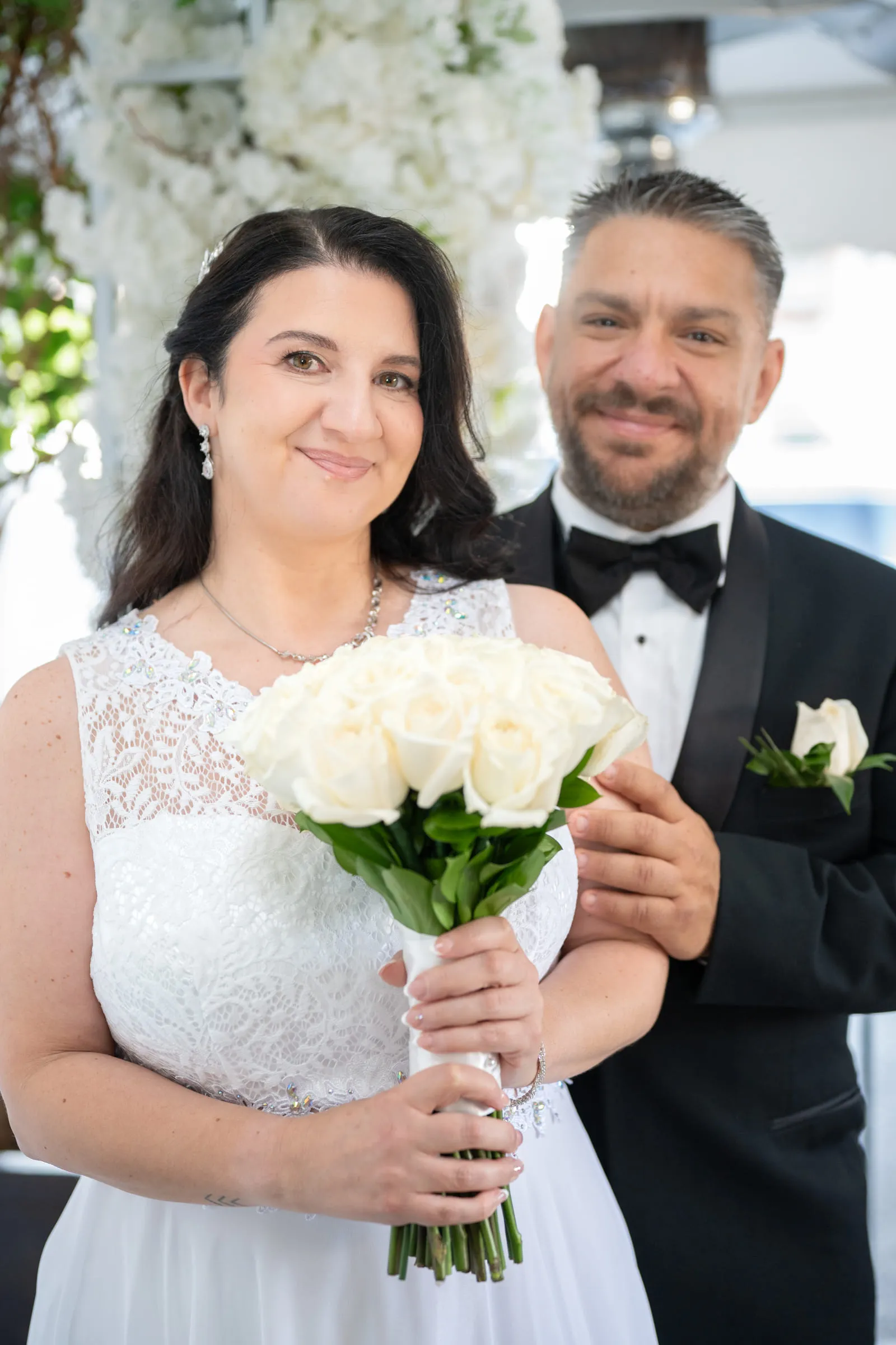 The bride and groom together beneath the white floral ceremony arch