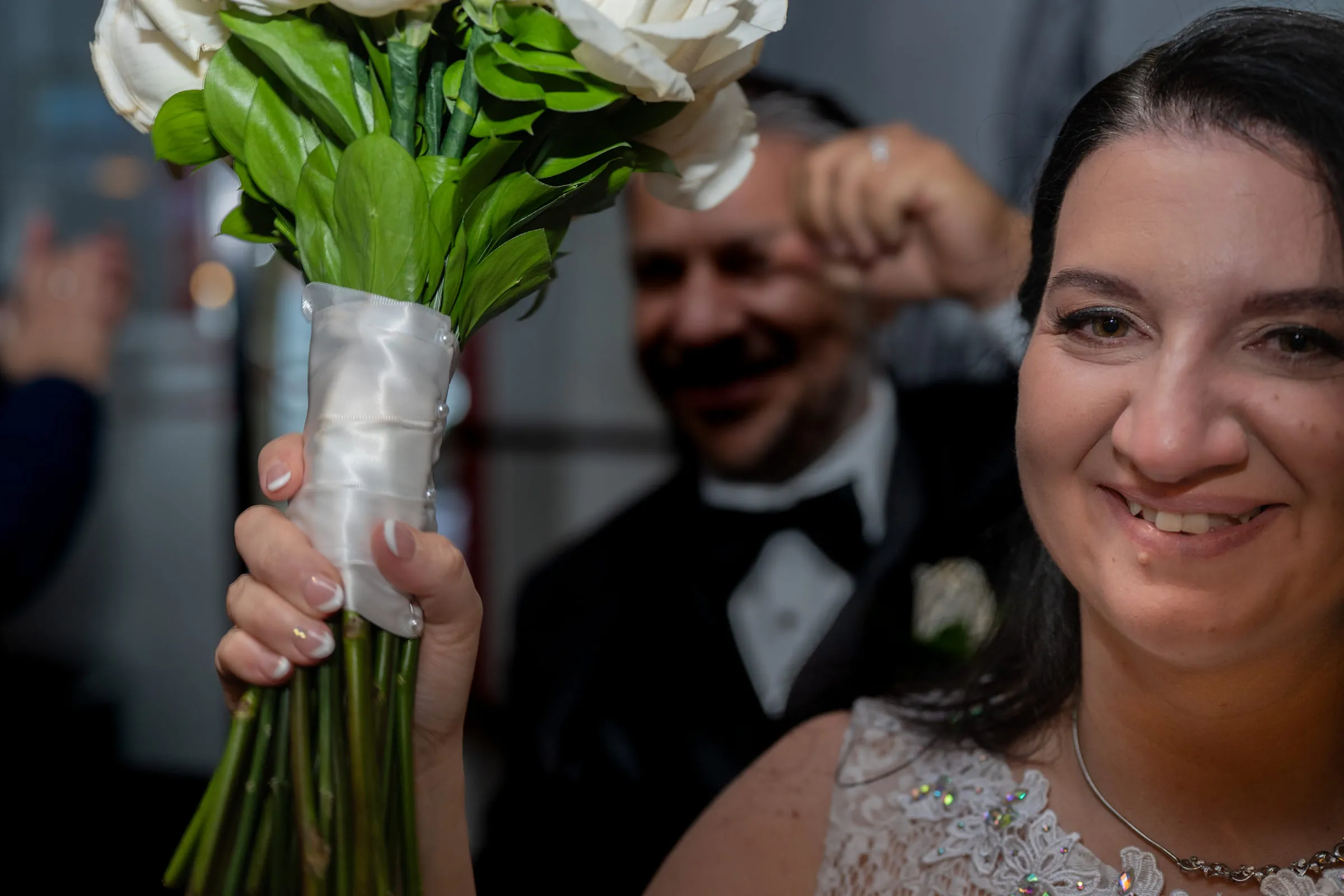 The bride laughing as the groom raises her bouquet behind her