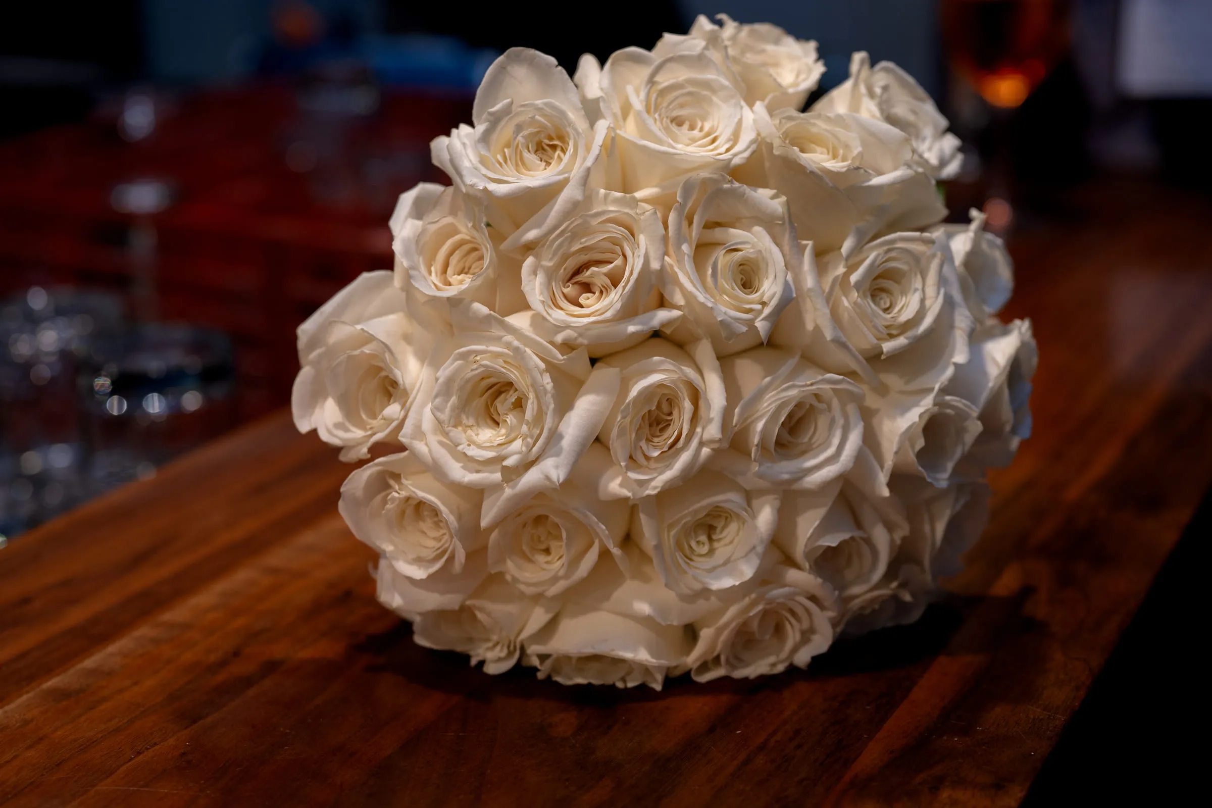 The bride’s bouquet of white roses resting on a wooden table